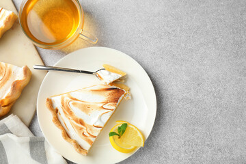 Slice of tasty lemon meringue tart with mint served on light grey table, flat lay. Space for text