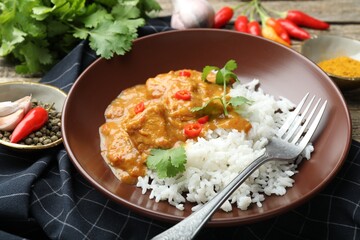 Chicken tikka masala with rice served on wooden table, closeup