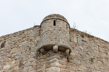 A close view of an old stone wall featuring a rounded turret. Budva old town © evannovostro