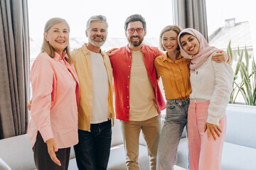 Diverse group of smiling happy multinational business people wearing casual clothes embracing