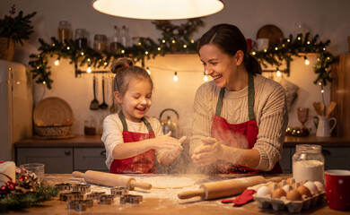 Mother and daughter cooking festive treats in decorated kitchen