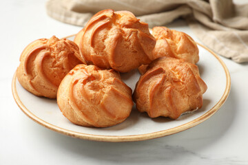 Fresh tasty profiteroles on white marble table, closeup