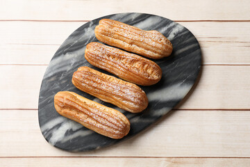 Delicious eclairs on white wooden table, top view