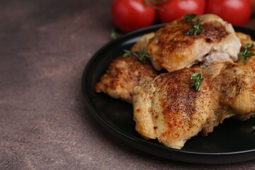 Tasty cooked chicken thighs with thyme and tomatoes on brown table, closeup. Space for text