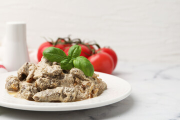 Tasty beef Stroganoff with basil and tomatoes on white marble table, closeup. Space for text
