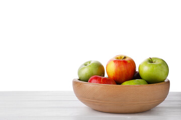 Red and green ripe apples in bowl on wooden table against white background