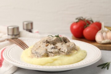 Delicious beef stroganoff with mashed potatoes and rosemary served on light table, closeup. Space for text