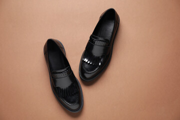 Pair of stylish loafer shoes on brown background, top view