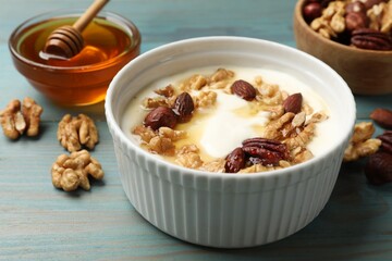 Delicious Greek yogurt with honey and nuts served on blue wooden table, closeup