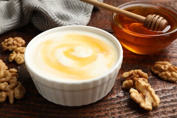 Delicious Greek yogurt with honey and walnuts served on wooden table, closeup