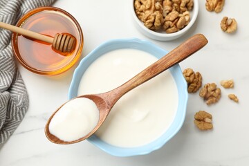 Delicious Greek yogurt with honey and walnuts served on white table, flat lay
