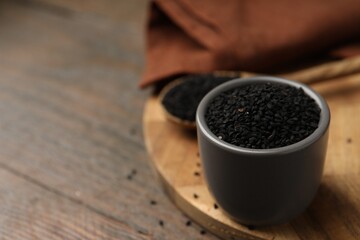 Aromatic black caraway in bowl and spoon on wooden table, closeup. Space for text