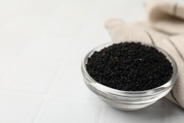 Aromatic black caraway in glass bowl on white table, closeup. Space for text
