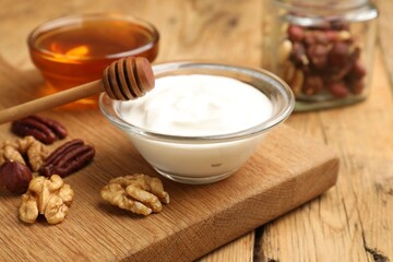 Delicious Greek yogurt with honey and nuts on wooden table, closeup