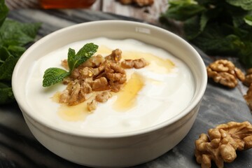 Delicious Greek yogurt with honey, nuts and mint on table, closeup