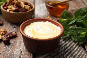 Delicious Greek yogurt with honey, nuts and mint on wooden table, closeup