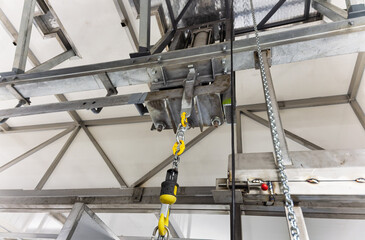 Industrial Swivel Crane Hook with safety latch assembly suspended from a metal frame. Ideal for hoisting and rigging operations in a commercial setting