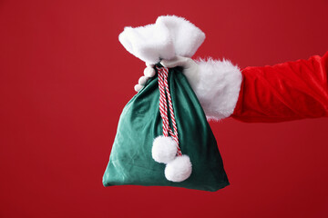 Santa Claus holding sack on red background, closeup. Merry Christmas and Happy New Year