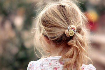 Little girl with blond hair and flower hair tie faces away from the viewer