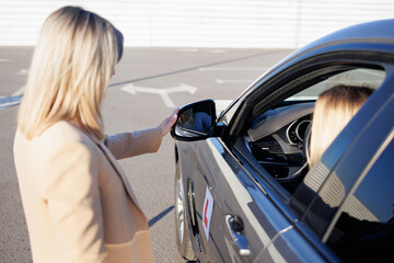 Instructor Adjusting Side Mirror for Student Driver before Driving Lesson