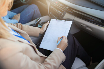 Driving Test Assessment Form – Instructor Filling Out Practical Evaluation Checklist in Car