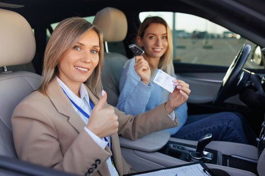 Instructor and New Driver Smiling with License After Test