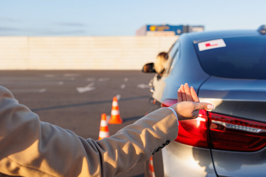 Instructor Giving Hand Signals to Learner Driver During Maneuver Training
