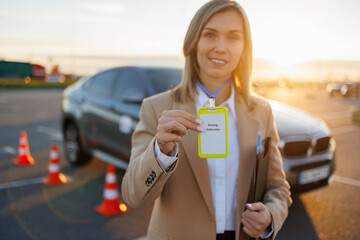 Professional driving instructor showing identification badge at training area