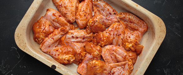 Raw marinated chicken wings spices red sauce paprika baking tray cooking top view