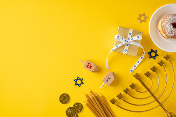 Bright yellow backdrop with a menorah, gift box tied with blue and white ribbon, dreidels, coins, and a plate with pastry, capturing Hanukkah celebration and festive greeting