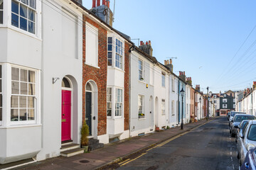 Old colourful terraced houses line a street in a city centre under blue sky in spring