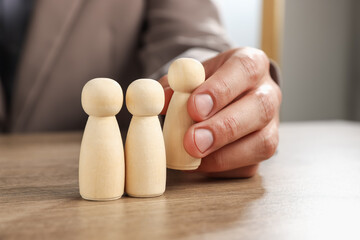 Man with human figures at wooden table, closeup