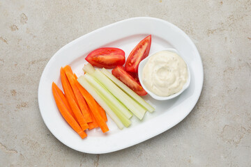 Different fresh vegetables and sauce on light grey table, top view