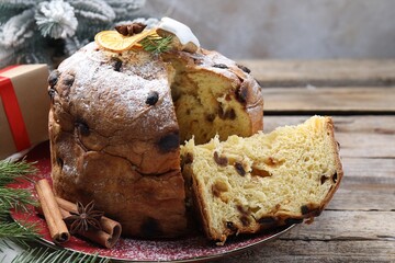 Tasty Christmas panettone cake with powdered sugar and festive decor on wooden table, closeup