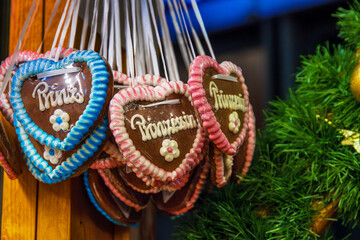Princess themed lebkuchen hearts. A closeup of colorful heart shaped gingerbread decorated with the word prinzessin hanging at festive christmas market stall
