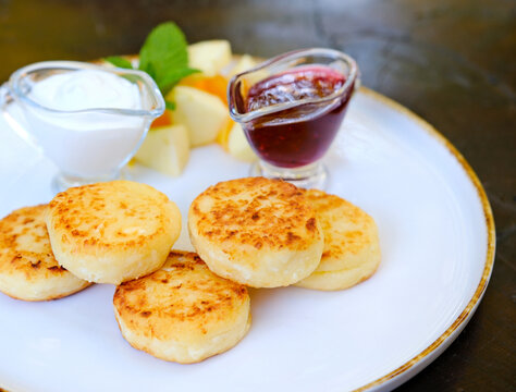 Homemade pancakes with yoghurt, berries and raspberry jam. Pancake day breakfast on beige tile background, top view. Vertical. High quality photo