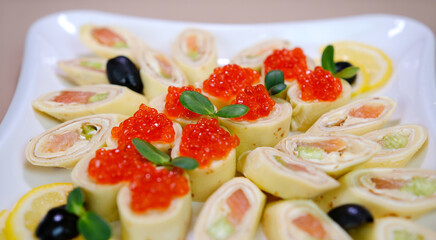 Delicious thin pancakes with red caviar on plate, closeup. thin pancakes with caviar and red fish