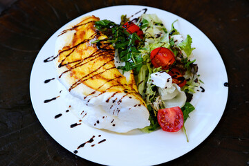 protein omelet salad drizzle Freshly made omelet drizzled , served alongside a crisp green salad . Elegant breakfast or brunch dish on a white plate with coffee in the background. High quality 