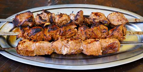 Shashlik or shish kebab prepared on barbecue grill over hot charcoal with grilled vegetables. Grilled pieces of pork meat on metal skewers. High quality photo