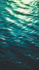 Sea water with small waves illuminated by the warm afternoon sun, creating a calm and glowing coastal scene.
