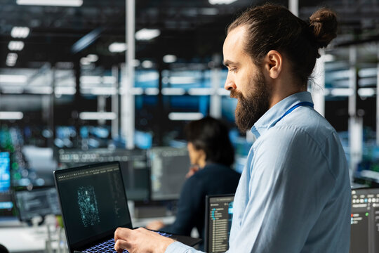 Engineer in server room using AI LLM assistant on laptop to review hardware diagnostics. IT specialist in data center analyzing performance data using large language model to maintain system uptime