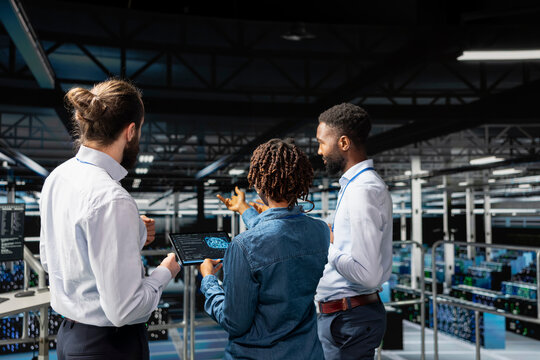 Server farm coworkers overseeing work done reviewing neural network code and LLM visualization for datasets. Team of technicians monitoring AI system performance, industrial platform.