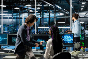 Data center manager teaching intern how to run AI forecasting simulations, tracking performance. Server hub supervisor helping trainee learn to integrate machine learning APIs into software platforms