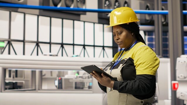 Technician overseeing solar energy installation process, troubleshooting automated machinery, calibrating robotic arms in renewable energy manufacturing facility, camera B