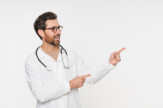 Male practitioner doctor surgeon wear white robe pointing to empty space for advertisement logo offer promotion isolated on white background. Health life insurance, healthcare and medicine. - Powered by Adobe