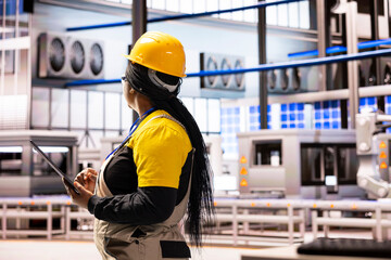 Power plant engineer conducting equipment assessments, looking around the facility with tablet in hand. African American factory manager overseeing digital simulations of manufacturing processes.