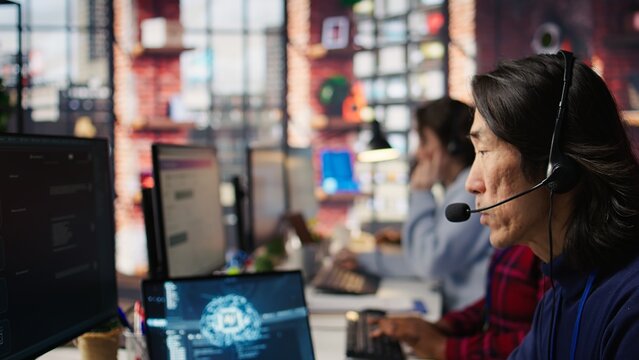 Call center agents track shipments in office using AI chatbot for help. Customer center workers use artificial intelligence assistance to locate clients packages and provide status updates, camera B