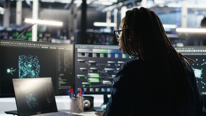 Server farm software developer interprets AI generated data analytics graphs. Data center specialist using artificial intelligence program showing predictive system metrics, camera B