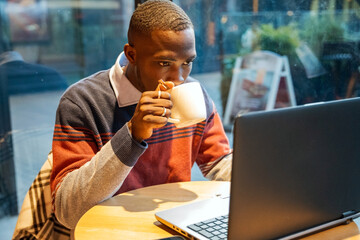 Enjoying coffee while working on a laptop in a cozy cafe during a busy afternoon