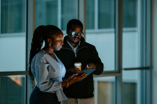 Colleagues collaborating on tablet at night office